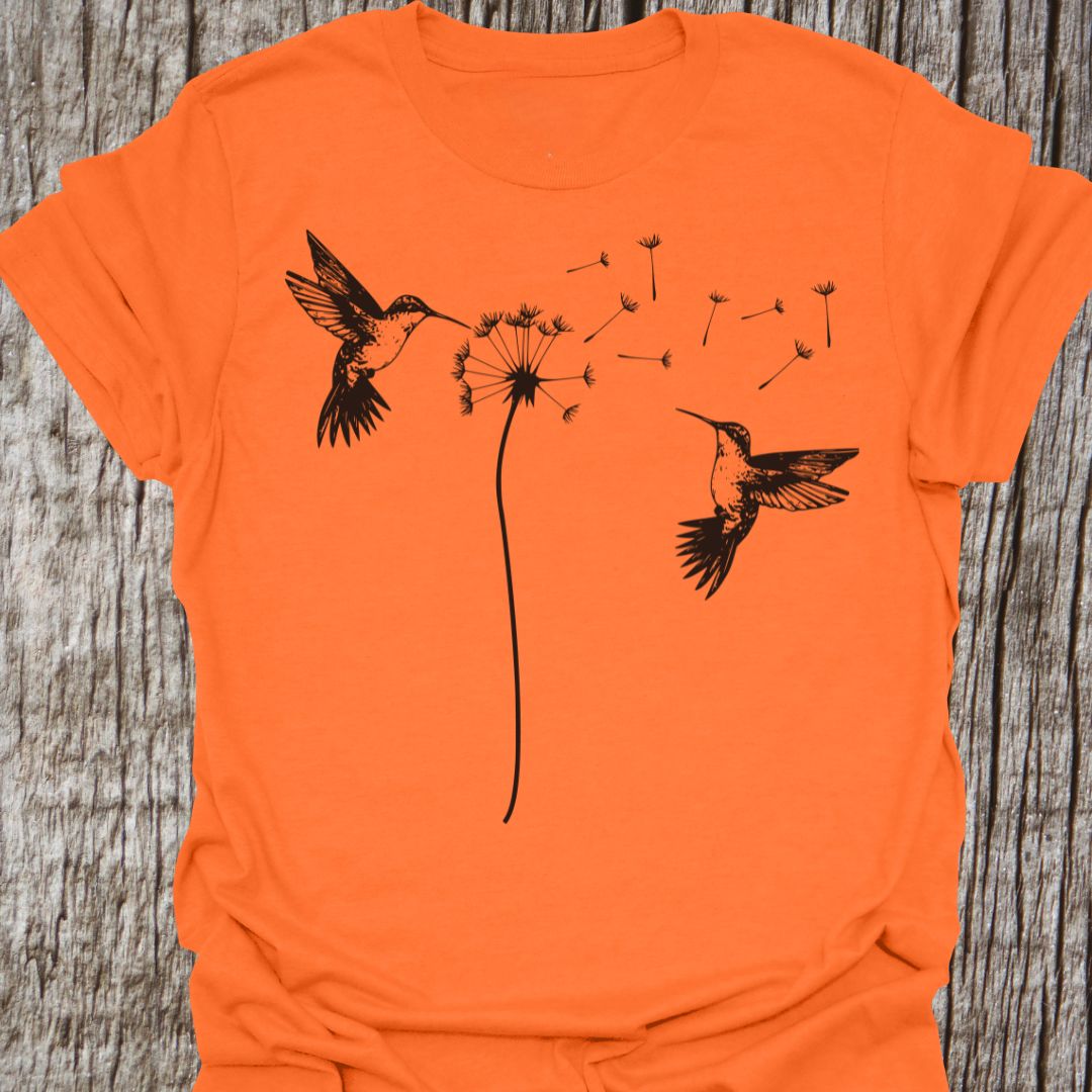 Two humming birds hovering at Dandelion in black on orange t-shirt