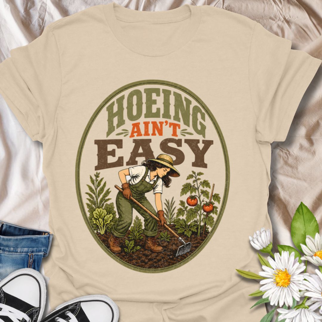 This Hoeing Ain’t Easy t-shirt is made for gardeners who know that growing tomatoes, tending soil, and keeping the garden alive takes real work. The vintage-inspired design features a gardener using a hoe among vegetables, leafy plants, tomatoes, and rich garden soil, giving it a funny but classic homestead garden feel. Perfect for backyard gardeners, vegetable growers, allotment keepers, homesteaders, tomato gardeners, plant lovers, and anyone who knows garden chores are worth it.