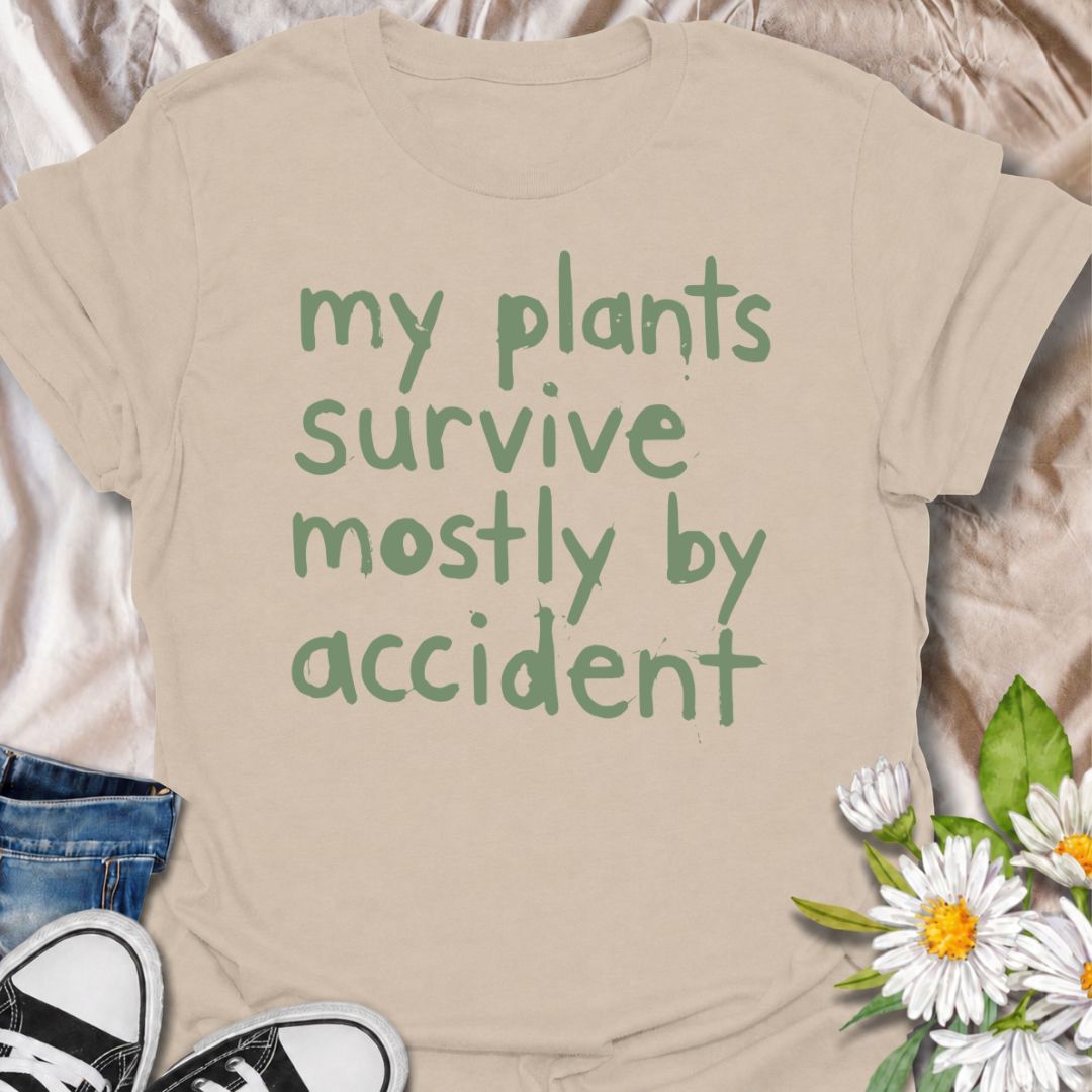 A funny plant T-shirt for anyone whose houseplants are doing surprisingly well despite a slightly questionable care routine. The phrase “My Plants Survive Mostly by Accident” delivers dry, self-deprecating humor that plant parents and indoor gardeners will instantly relate to. Its simple hand-drawn typography keeps the design casual, modern, and easy to wear. It makes a great gift for houseplant lovers, accidental green thumbs, and anyone who is still figuring out what their plants actually need. Perfect fo