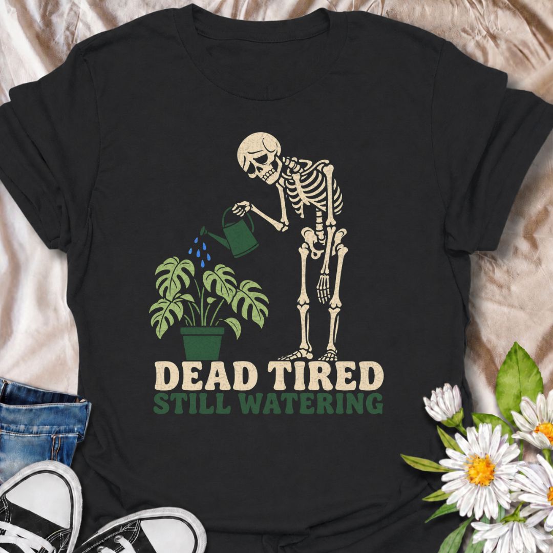 A funny plant T-shirt for anyone who is exhausted but still somehow finds the energy to water the plants. The phrase “Dead Tired, Still Watering” pairs with a weary skeleton and drooping houseplant for dark, relatable plant-parent humor. It is perfect for houseplant lovers, indoor gardeners, and anyone whose plant-care routine continues no matter how tired they are. The bold character-led design makes a great gift for plant collectors who like their botanical humor a little darker. Ideal for nursery trips,