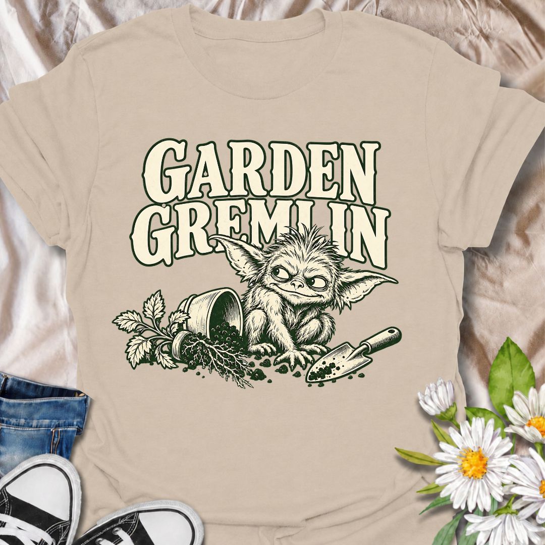 A funny gardening T-shirt for anyone who turns a simple garden job into a slightly chaotic adventure. Featuring a mischievous little garden gremlin beside spilled soil, a tipped plant pot, and a hand trowel, this design is packed with personality and relatable garden humor. The bold “Garden Gremlin” phrase makes it perfect for backyard gardeners, plant lovers, and anyone who is rarely clean or organized once gardening starts. It makes a fun gift for gardeners who embrace the mess, the dirt, and the occasion