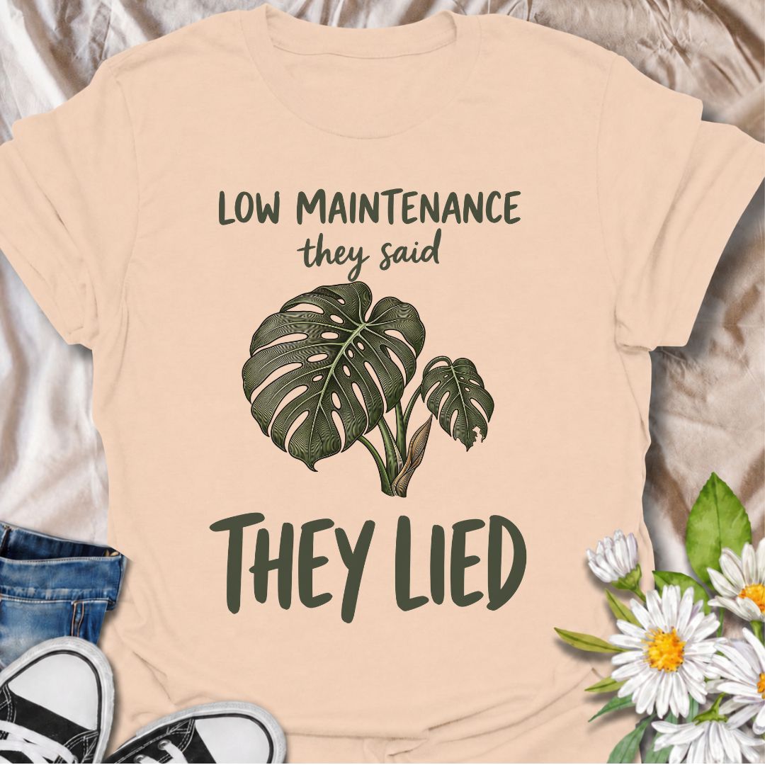 A funny plant T-shirt for anyone who was promised an easy-care houseplant and quickly discovered otherwise. The phrase “Low Maintenance, They Said. They Lied.” delivers dry, relatable humor that plant parents and monstera lovers will instantly understand. Featuring a leafy monstera illustration, the design feels simple, wearable, and clearly rooted in houseplant culture. It makes a great gift for indoor gardeners, plant collectors, and anyone who has spent far more time troubleshooting a supposedly easy pla