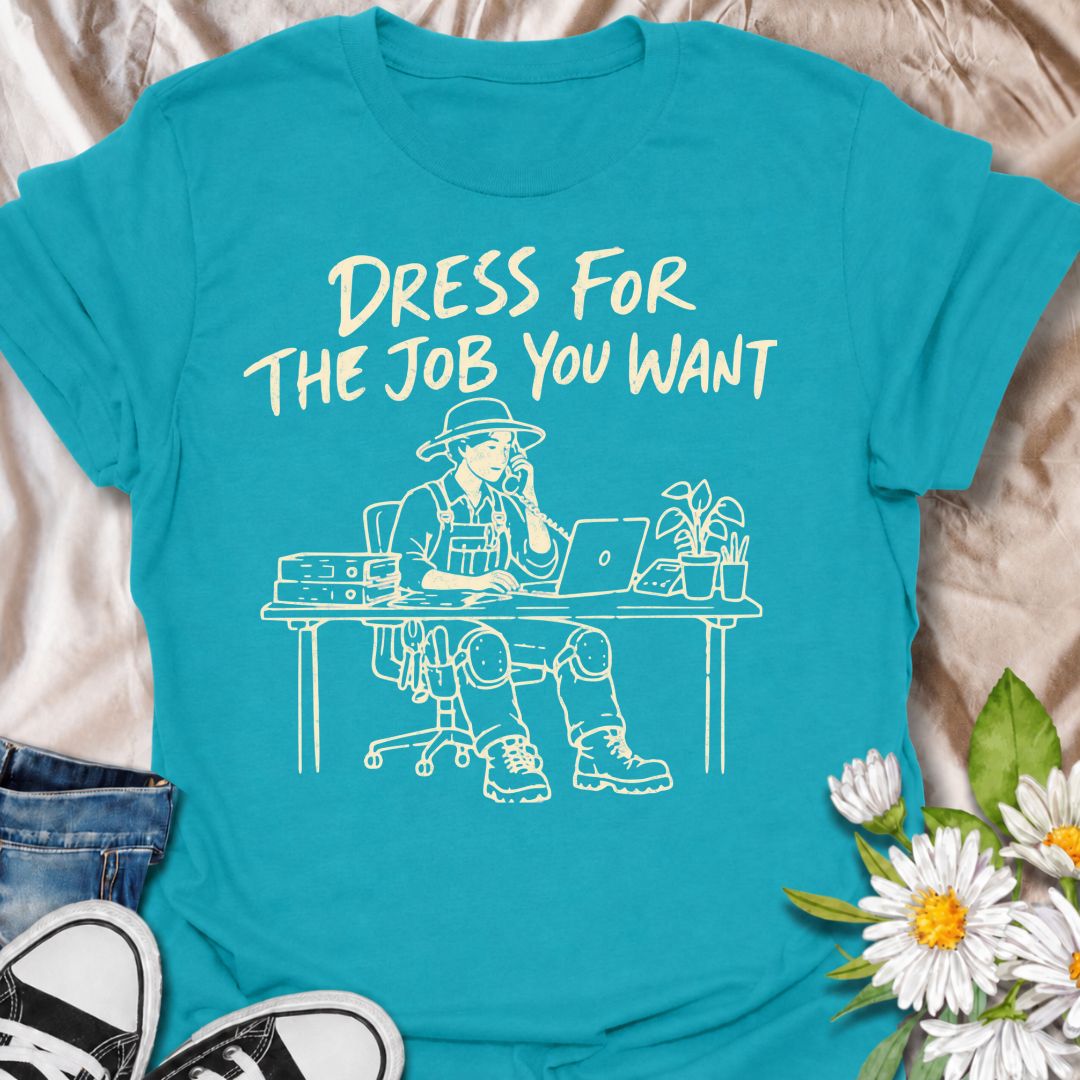 A funny gardening T-shirt for anyone who would rather be dressed for the garden than stuck behind a desk. The phrase “Dress for the Job You Want” pairs with a gardener in full work gear sitting in an office setting for a dry, absurd bit of garden humor. Featuring overalls, knee pads, work boots, tools, a laptop, and desk accessories, the design is perfect for gardeners who know exactly where they would rather be. It makes a great gift for professional gardeners, backyard growers, plant lovers, and anyone dr