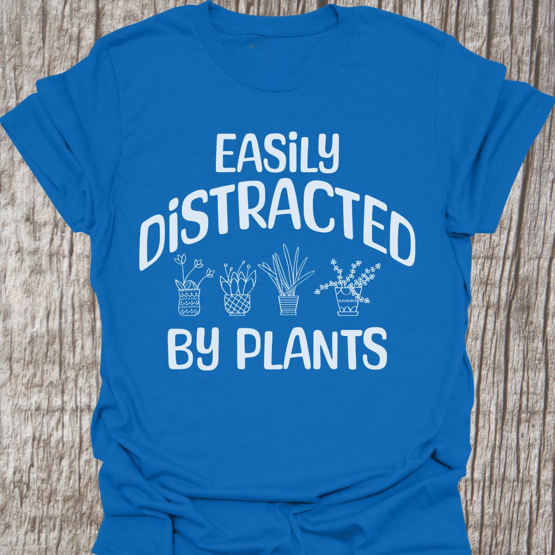 Easily Distracted By Plants in white Text with image of four small pot plants, all in white. This is on a royal blue T-shirt
