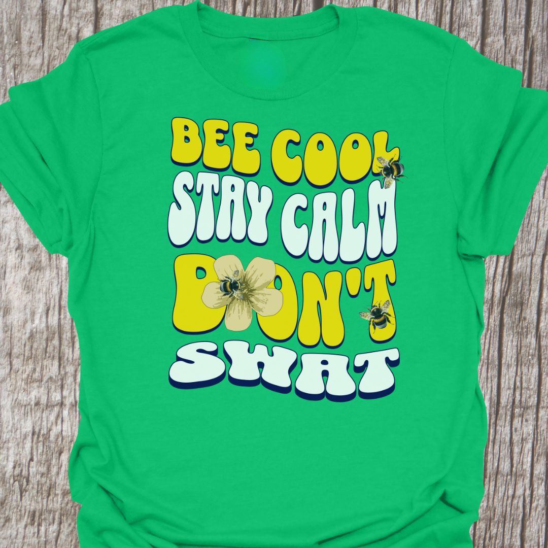 "Bee Cool, Stay Calm, Don't Swat" shaped text in white and yellow with images of bees and flowers. Irish green colored T-shirt