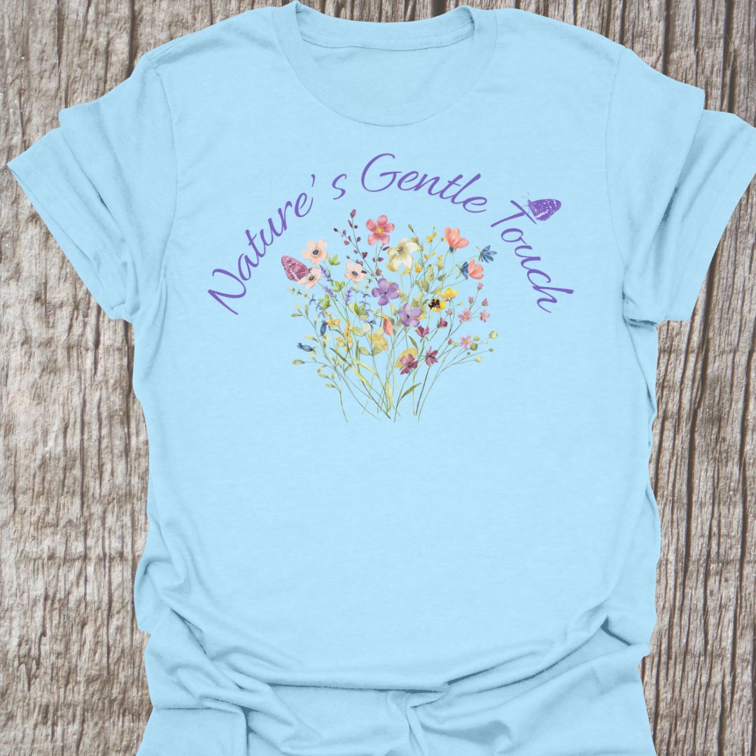 Beautiful flowers light blue T-shirt, 'Nature's Gentle Touch' curving around flowers in a lilac font, and a butterfly gently resting within the design.