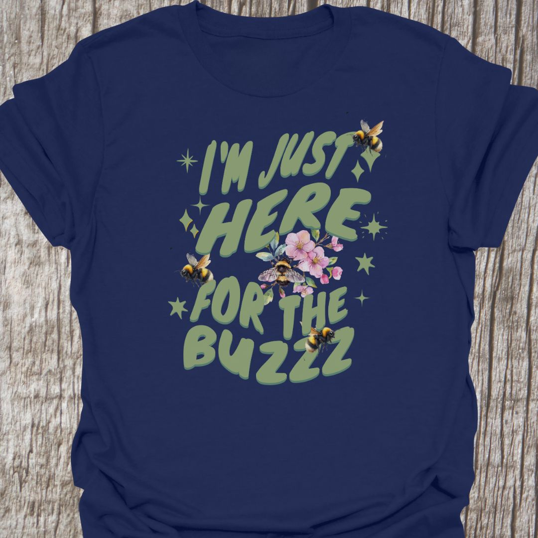 I am Just Here For The Buzz navy T-shirt, featuring a green text design adorned with bees and flowers for decoration