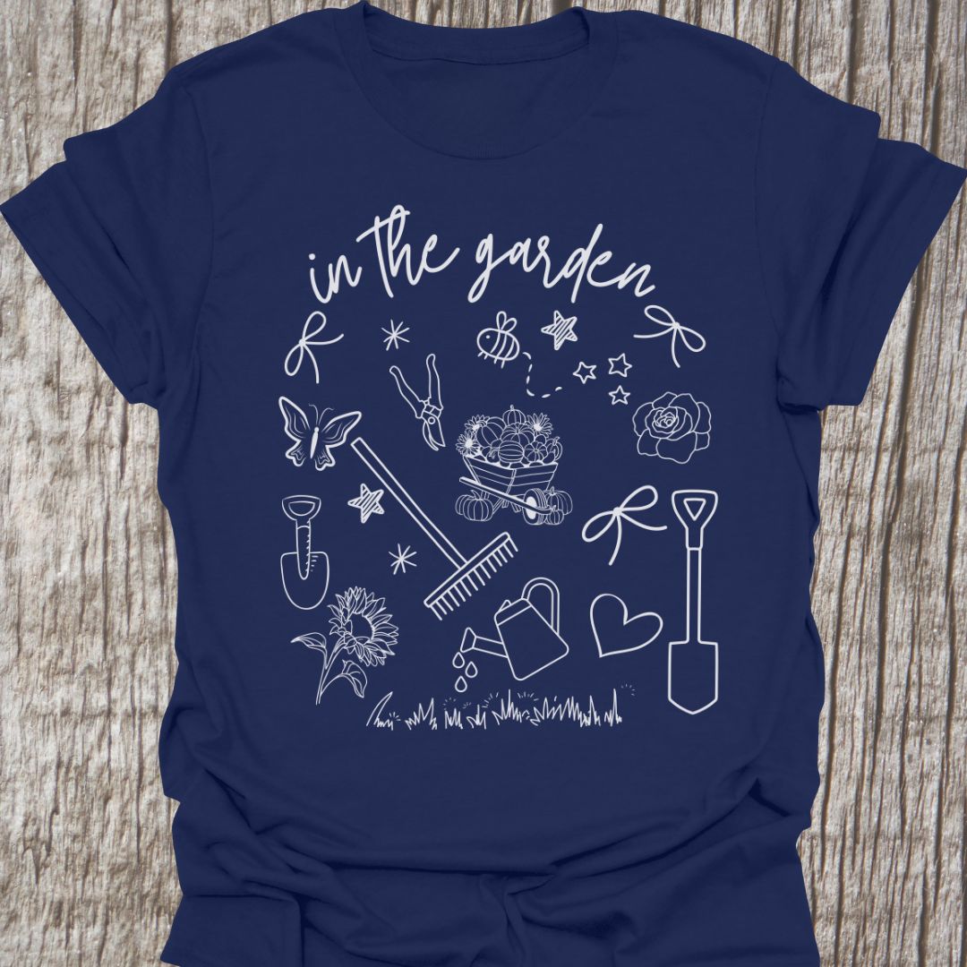 Garden Doodle on a T-shirt! This doodle has garden tools, flowers, grass, bees, butterfly and lots more, white images and text saying 'in the garden' on a navy-shirt