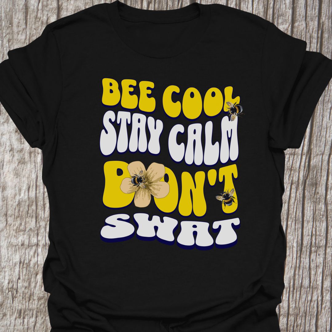 "Bee Cool, Stay Calm, Don't Swat" shaped text in white and yellow with images of bees and flowers. Black colored T-shirt
