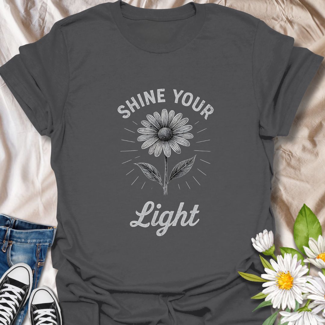 Spread positivity with this uplifting graphic t-shirt featuring a blooming daisy and the inspirational phrase "Shine Your Light." Perfect for flower lovers, mindful living enthusiasts, and anyone who enjoys wearing motivational, nature-inspired apparel.