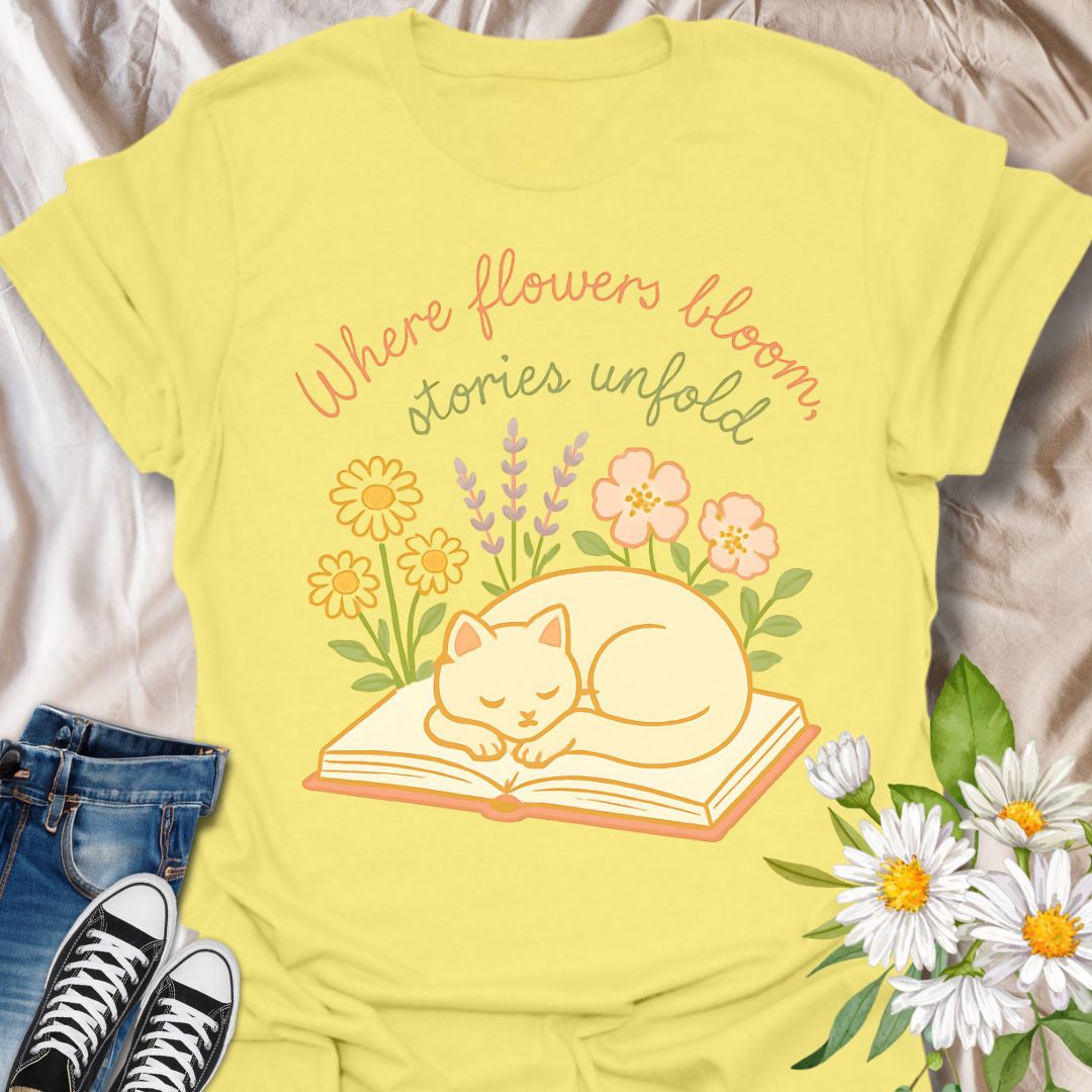 Cozy cat and book t-shirt with pastel flowers and the quote 'Where flowers bloom, stories unfold.' Perfect for book lovers, cat moms, gardeners, and daydreamers who adore cottagecore and literary aesthetics. Soft and sweet tee ideal for spring, reading nooks, and gifting.