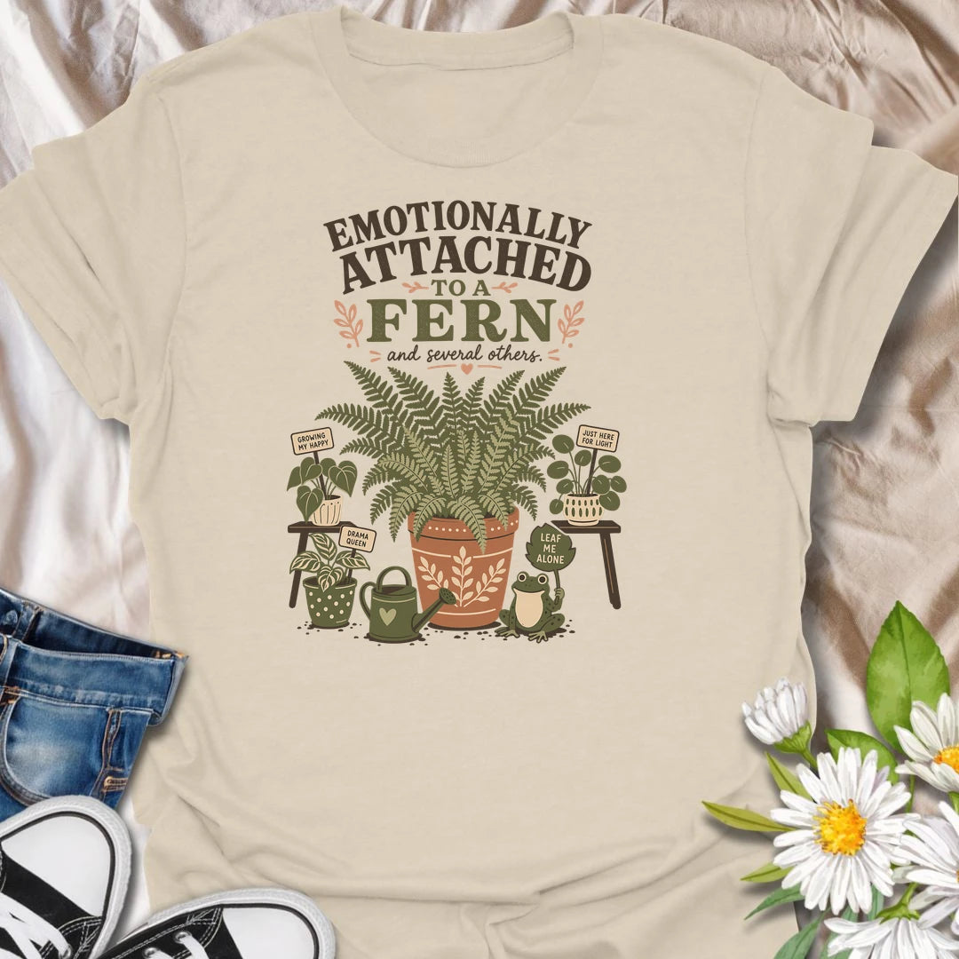 Celebrate your favorite leafy companion with this “Emotionally Attached to a Fern” T-shirt. Featuring a large decorative fern, houseplants, a watering can, and a cheerful frog, it is perfect for devoted plant parents. A charming gift for fern lovers, indoor gardeners, and botanical collectors.