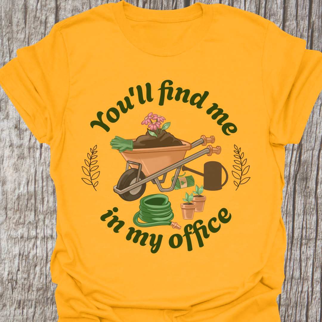 circular text 'You'll find me in my office' with wheelbarrow, hose, plants and watering can within circle all text in green on gold t-shirt