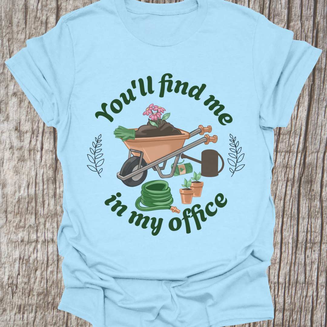 circular text 'You'll find me in my office' with wheelbarrow, hose, plants and watering can within circle all text in green on light blue t-shirt