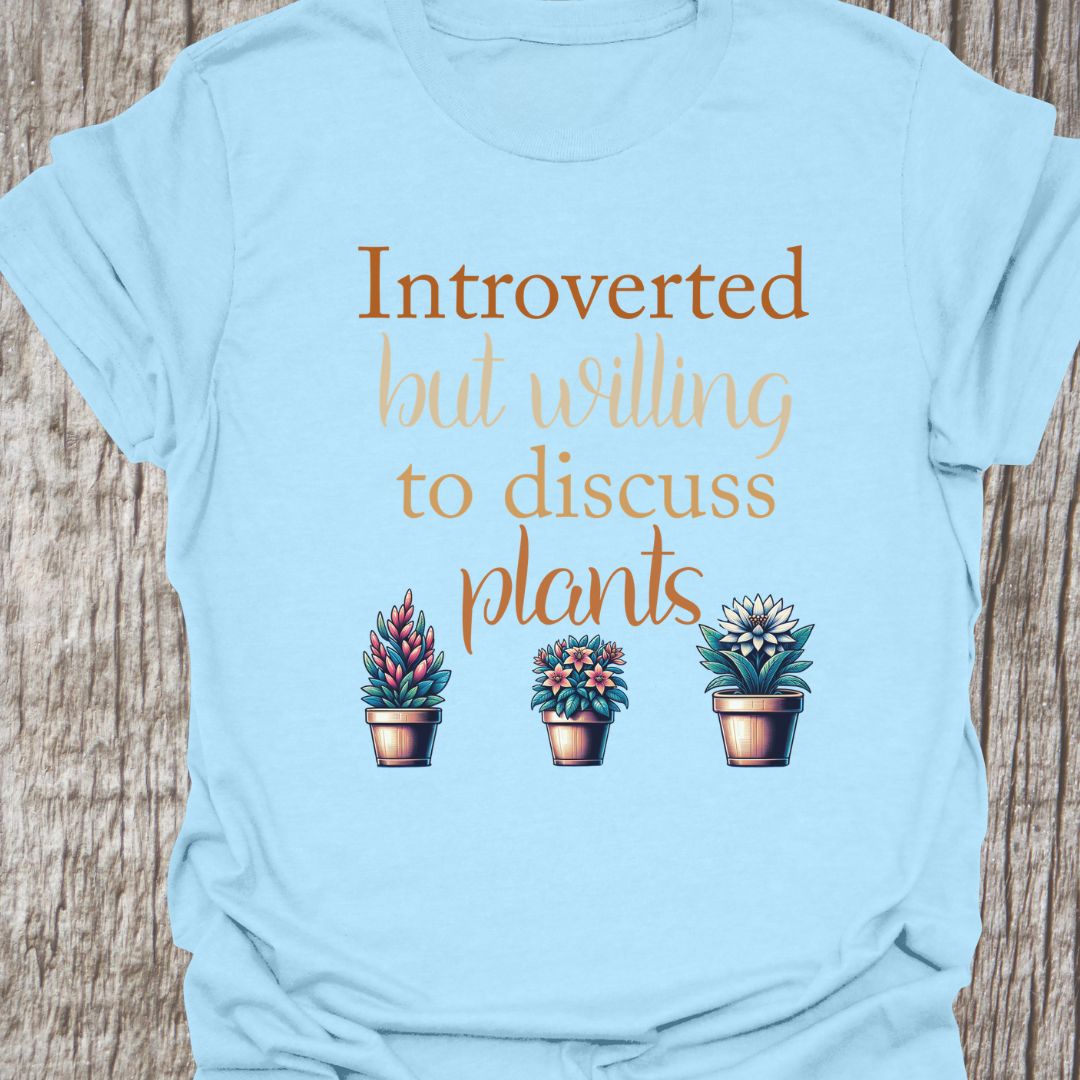 Introverted but willing to discuss plants in natural colored text with image of three flowering pot plants, on a light blue t-shirt