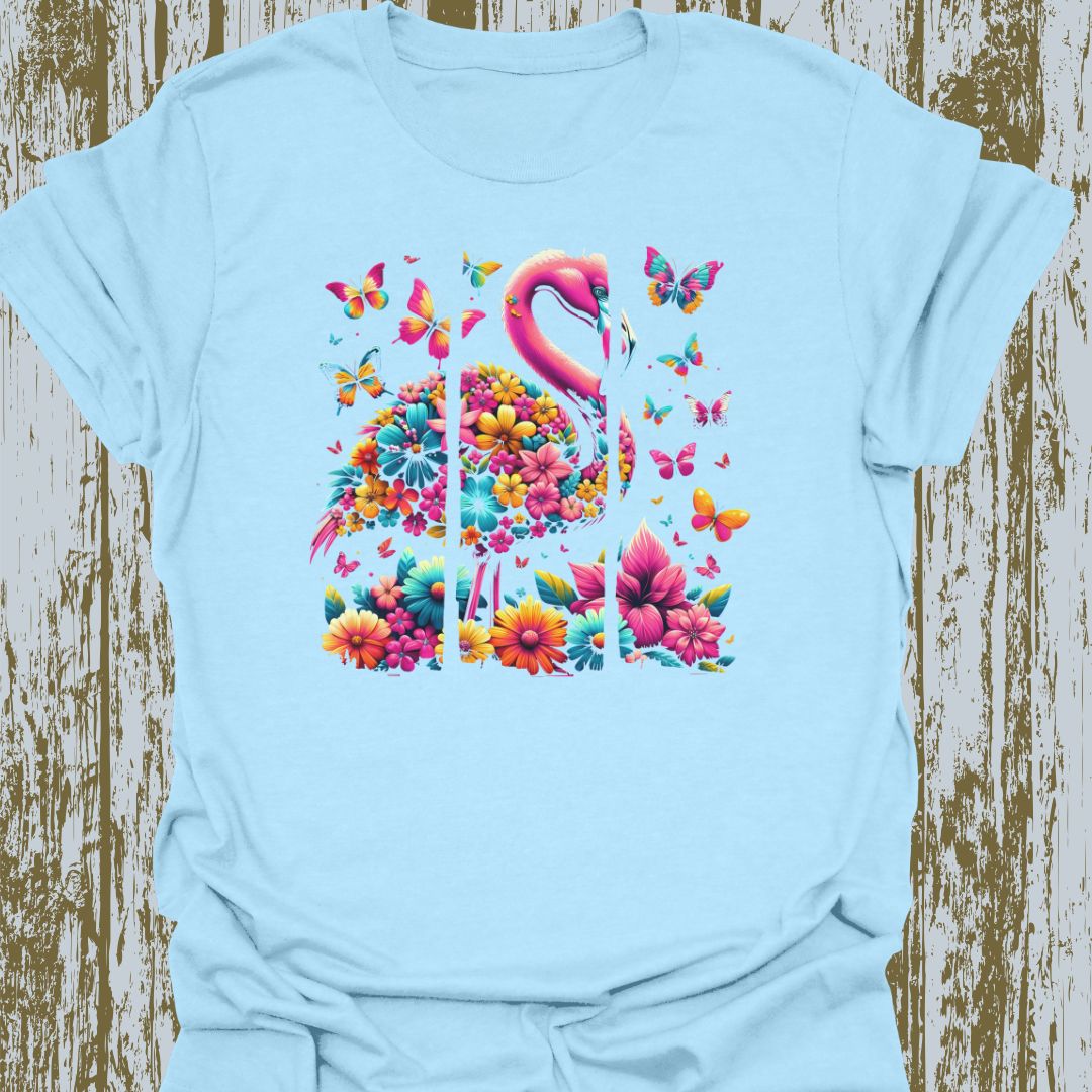 A design featuring flamingos, butterflies, and flowers in pink, yellow, and blue hues on light blue t-shirt.
