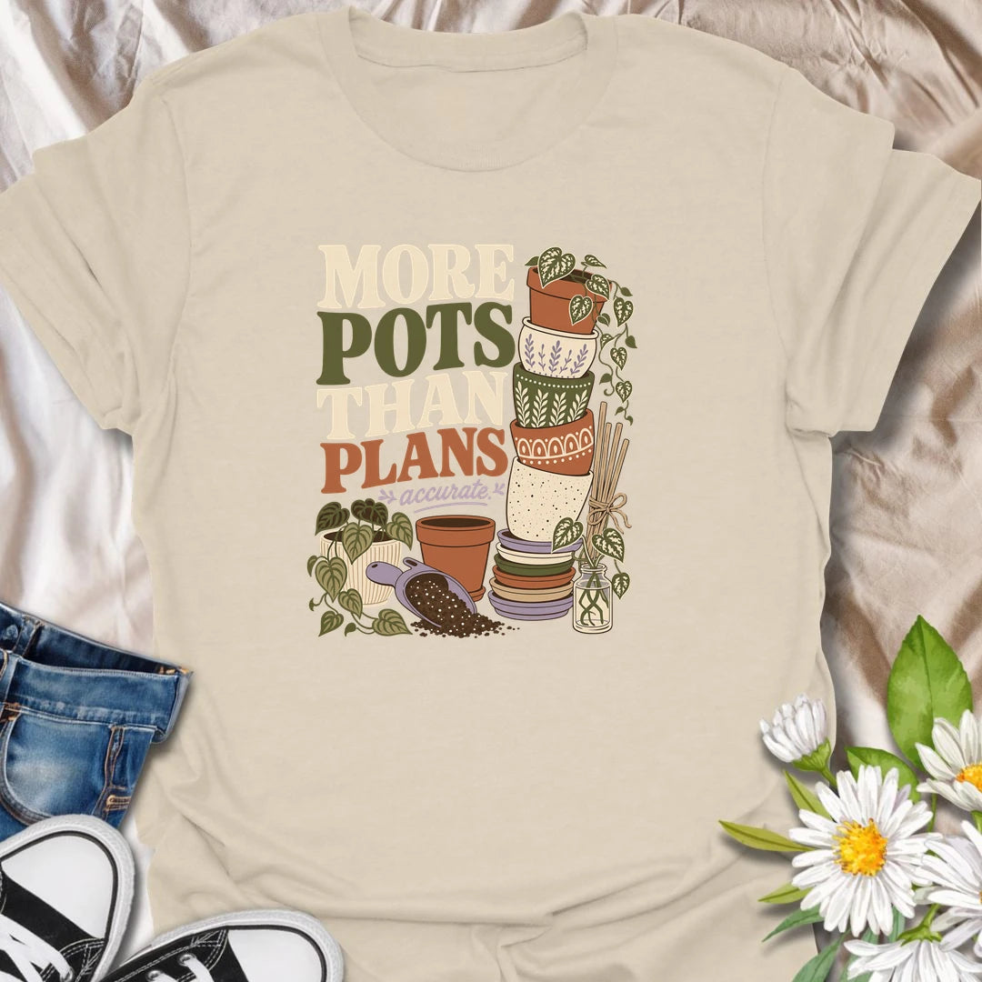 A relatable plant lover T-shirt for anyone whose pot collection has grown faster than their planting plans. The design features a tall stack of decorative pots, trailing houseplants, propagation cuttings, and potting soil. A fun gift for gardeners, plant collectors, and anyone who can never resist another beautiful planter.