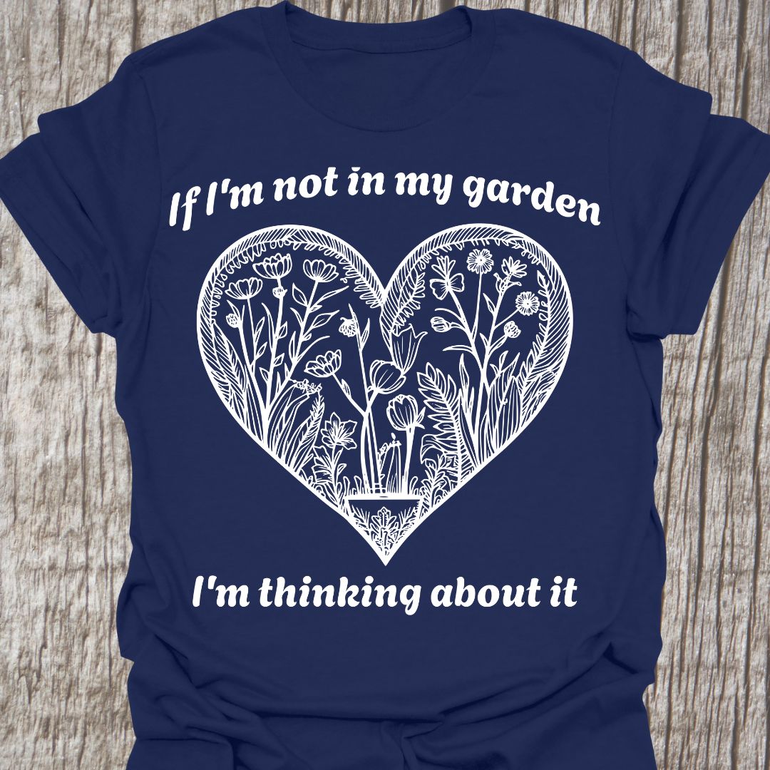 Text in white around a heart shape which contains flower images in white. Phrase above the heart is 'if I'm not in my garden' and below the heart 'I'm thinking about it', on a navy t-shirt
