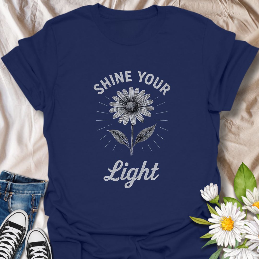 Spread positivity with this uplifting graphic t-shirt featuring a blooming daisy and the inspirational phrase "Shine Your Light." Perfect for flower lovers, mindful living enthusiasts, and anyone who enjoys wearing motivational, nature-inspired apparel.