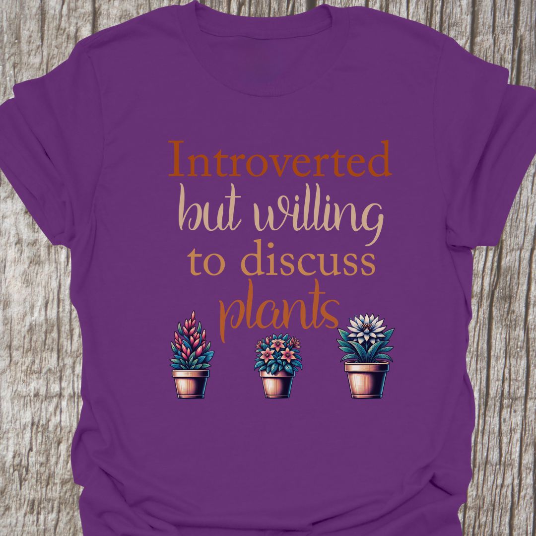 Introverted but willing to discuss plants in natural colored text with image of three flowering pot plants, on a purple t-shirt