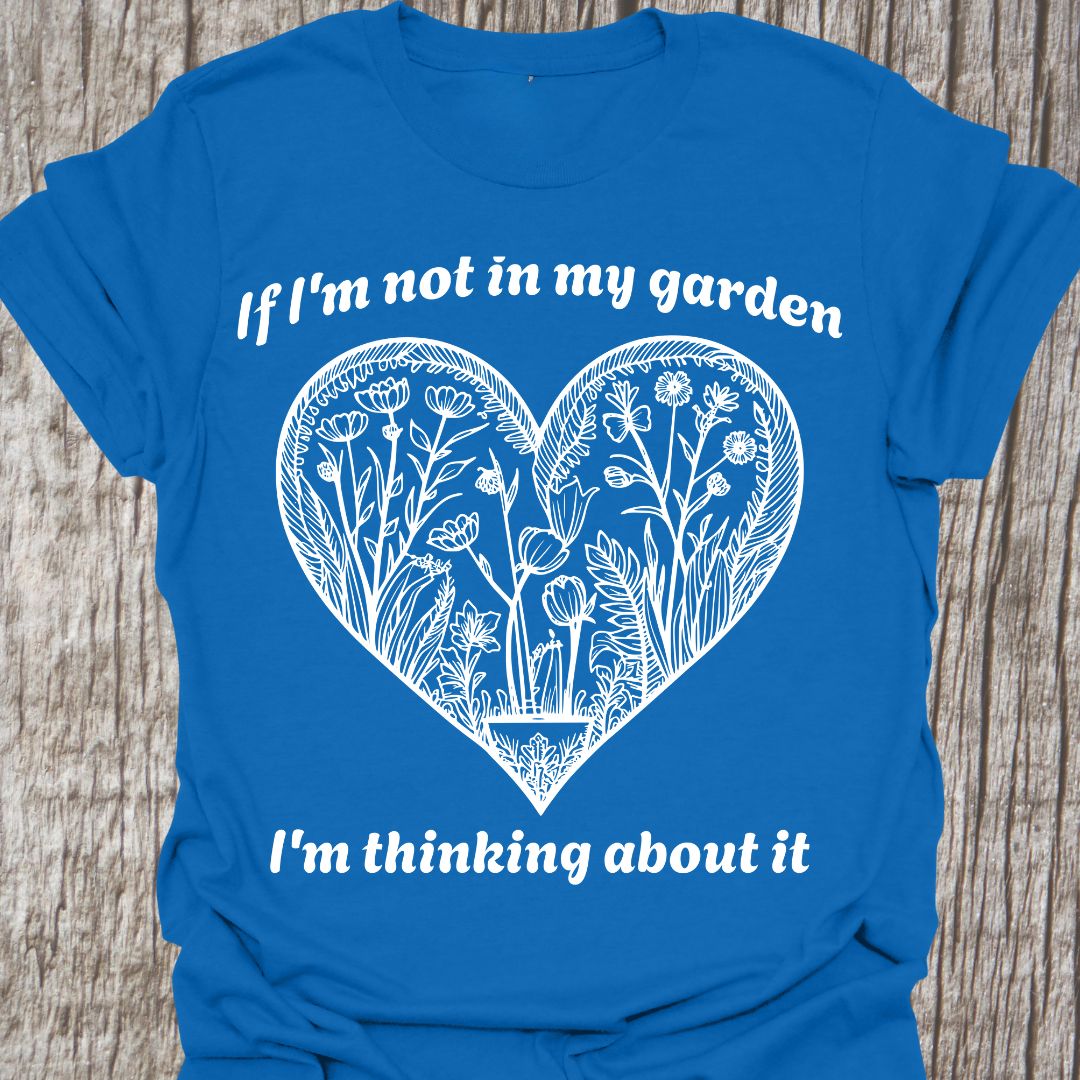 Text in white around a heart shape which contains flower images in white. Phrase above the heart is 'if I'm not in my garden' and below the heart 'I'm thinking about it', on a royal blue t-shirt