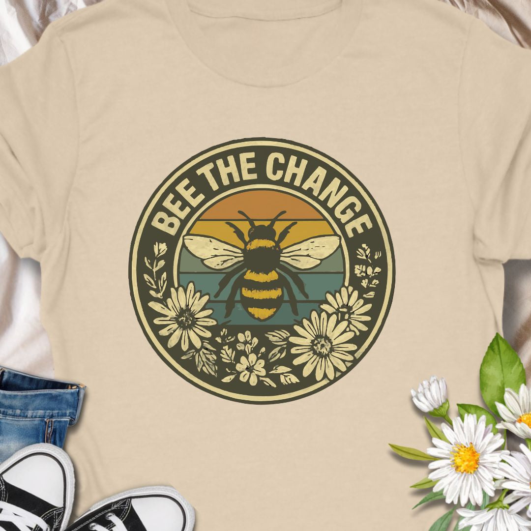 Spread positivity and environmental awareness with this vintage-style “Bee The Change” t-shirt. Featuring a bold bee illustration surrounded by wildflowers and retro sunset colors, it’s perfect for nature lovers, pollinator protectors, and eco-conscious souls. Makes a thoughtful gift for beekeepers, gardeners, or anyone who believes in making a difference—one bee at a time.