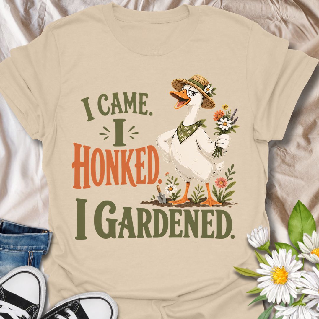 This I Came I Honked I Gardened t-shirt is made for gardeners who like their plant humor with a little chaotic goose energy. Featuring a confident garden goose in a straw hat holding flowers, surrounded by blooms, a trowel, soil, and bold vintage-style lettering, this design has a funny cottagecore garden feel. Perfect for gardeners, plant lovers, flower fans, goose lovers, backyard growers, and anyone who enjoys a playful botanical design with attitude.