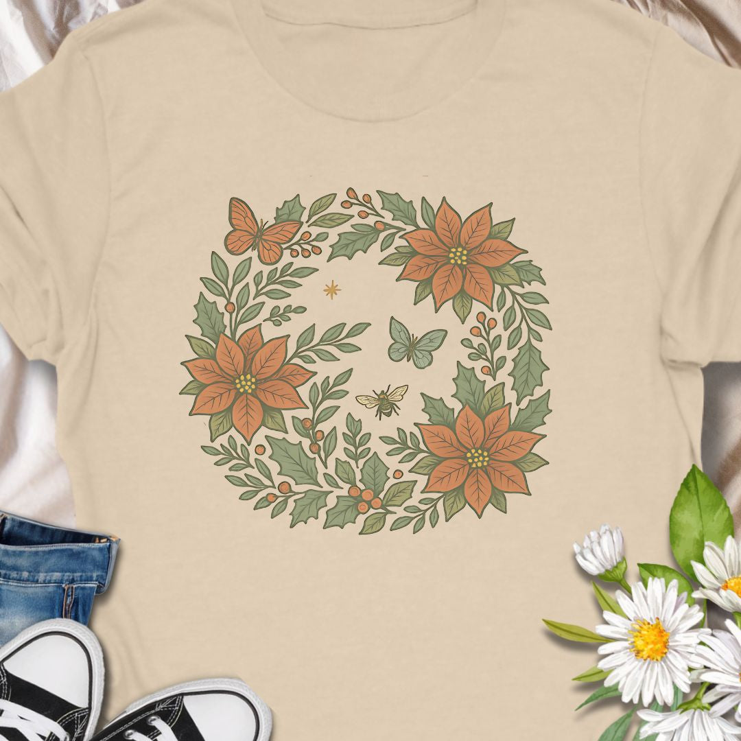 Festive botanical tee featuring a Christmas wreath with poinsettias, bees, and butterflies. Perfect holiday wear for plant lovers.