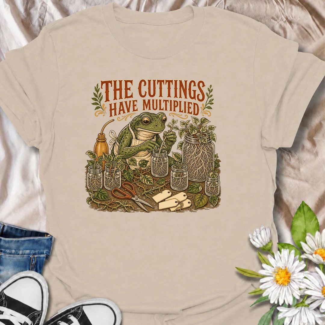 Celebrate a propagation collection that keeps growing with this funny “The Cuttings Have Multiplied” T-shirt. Featuring a charming frog surrounded by rooted plant cuttings, glass jars, scissors, and trailing vines, it is perfect for enthusiastic houseplant propagators. A playful gift for plant moms, pothos lovers, and anyone whose plant babies have taken over.
