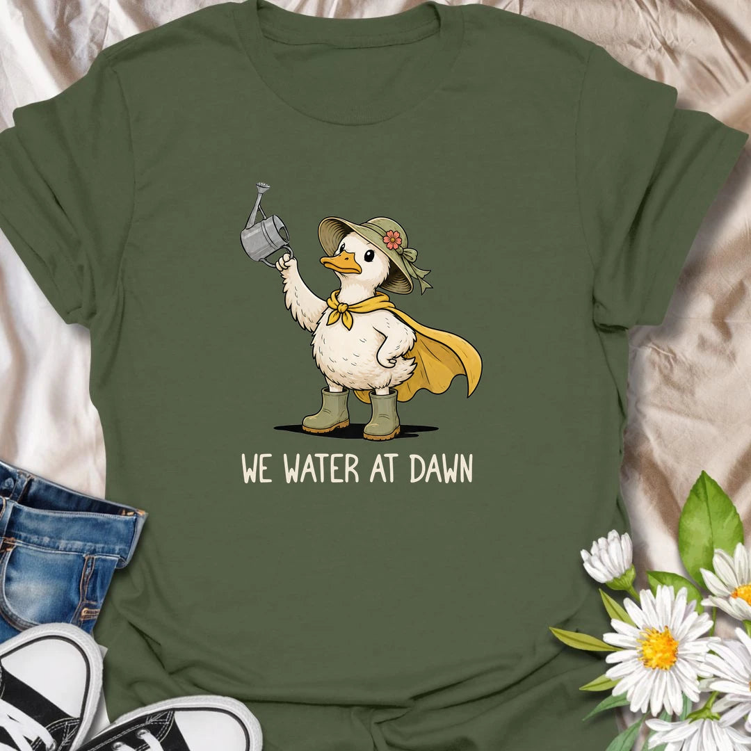 Water At Dawn t-shirt for gardeners who take their morning watering routine very seriously.
The cute duck gardener design adds playful garden charm with boots, a sunhat, cape, and watering can.
It is perfect for plant lovers, cottage garden fans, and anyone who starts the day checking on their flowers.
A sweet and funny gift for gardeners who believe the plants must be watered before anything else happens.