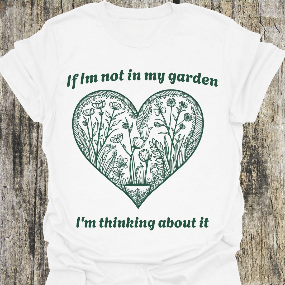 Text in green around a heart shape which contains flower images in green. Phrase above the heart is 'if I'm not in my garden' and below the heart 'I'm thinking about it', on a white t-shirt