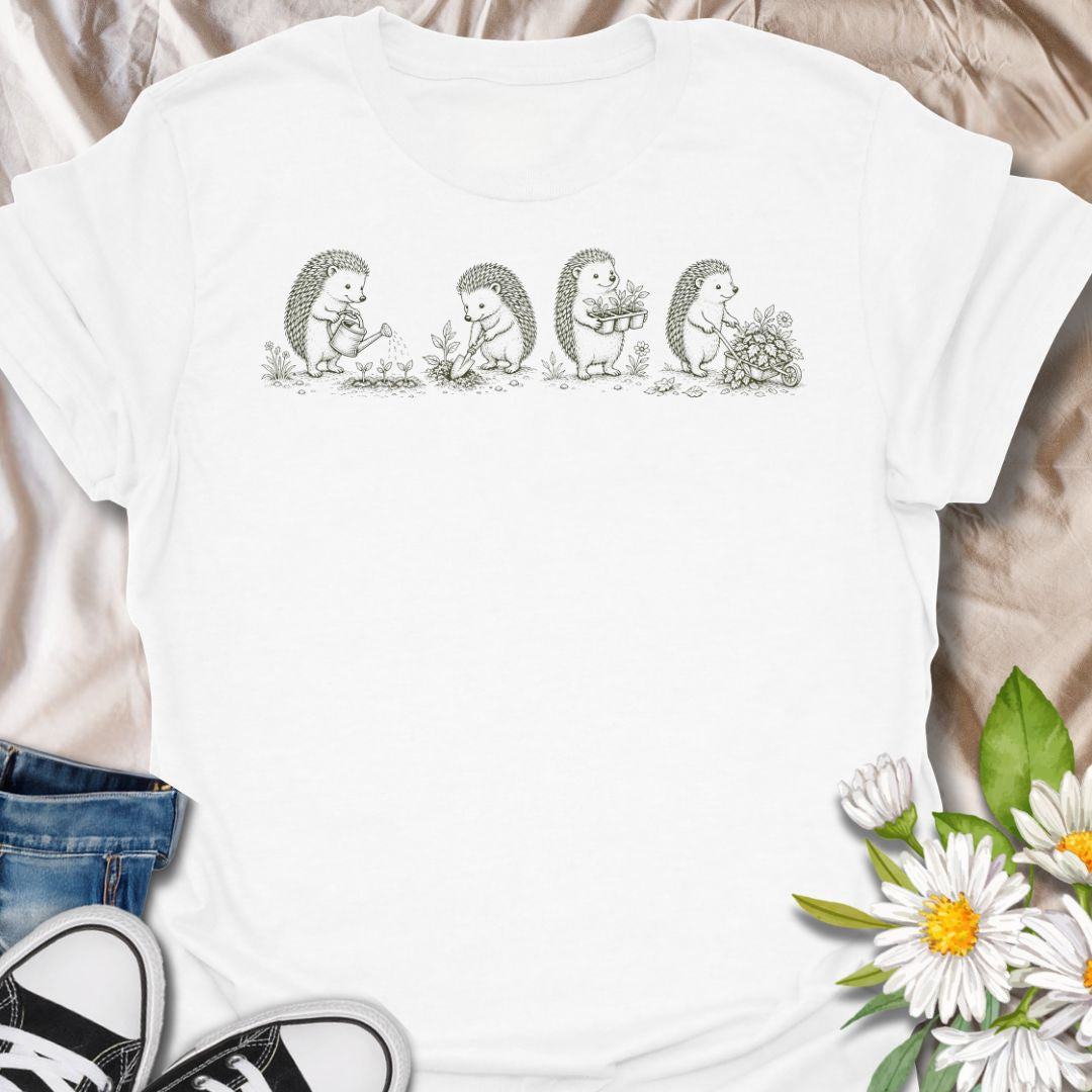 This Gardening Hedgehogs t-shirt is made for gardeners, nature lovers, and woodland animal fans who enjoy sweet vintage-style artwork. Featuring four charming hedgehogs watering, digging, carrying plants, and pushing a flower-filled wheelbarrow, this design has a gentle cottagecore garden feel. Perfect for plant lovers, gardeners, hedgehog fans, wildlife lovers, botanical art fans, and anyone who loves soft nature-inspired designs.