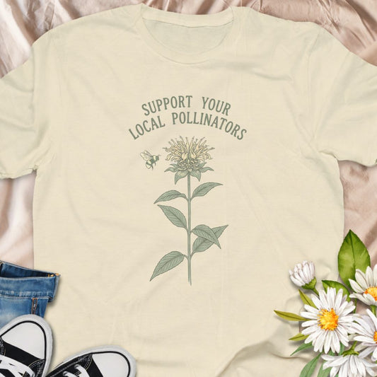 Show your love for bees and pollinator-friendly gardens with this “Support Your Local Pollinators” t-shirt. Featuring a botanical flower and bee illustration, this nature-inspired tee is perfect for gardeners, wildflower enthusiasts, and anyone passionate about helping pollinators thrive. A thoughtful gift for plant lovers and eco-conscious gardeners.