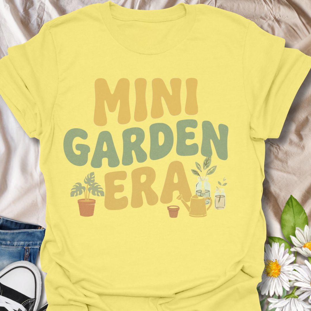 Retro-inspired plant lover t-shirt featuring the phrase “Mini Garden Era” with charming plant and watering can graphics. A fun tee for plant parents, indoor gardeners, houseplant lovers, and anyone embracing their small-space gardening phase.