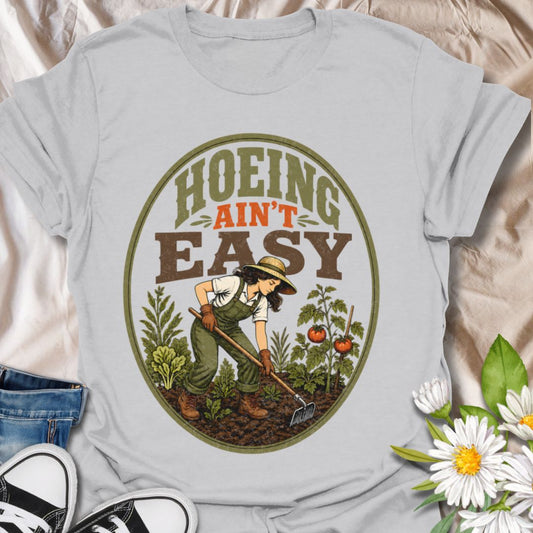 This Hoeing Ain’t Easy t-shirt is made for gardeners who know that growing tomatoes, tending soil, and keeping the garden alive takes real work. The vintage-inspired design features a gardener using a hoe among vegetables, leafy plants, tomatoes, and rich garden soil, giving it a funny but classic homestead garden feel. Perfect for backyard gardeners, vegetable growers, allotment keepers, homesteaders, tomato gardeners, plant lovers, and anyone who knows garden chores are worth it.