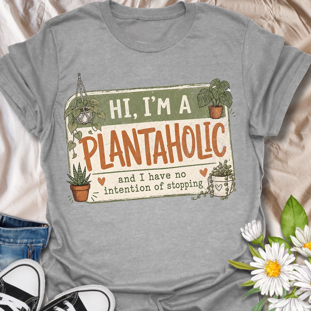 This Hi, I’m A Plantaholic t-shirt is perfect for plant lovers who can never resist one more houseplant. Featuring a playful badge-style layout with potted plants, trailing vines, and the phrase and I have no intention of stopping, this design brings a fun and relatable plant-parent vibe to any casual outfit. A great gift for plant moms, houseplant collectors, propagation fans, indoor gardeners, and anyone proudly obsessed with their growing plant collection.