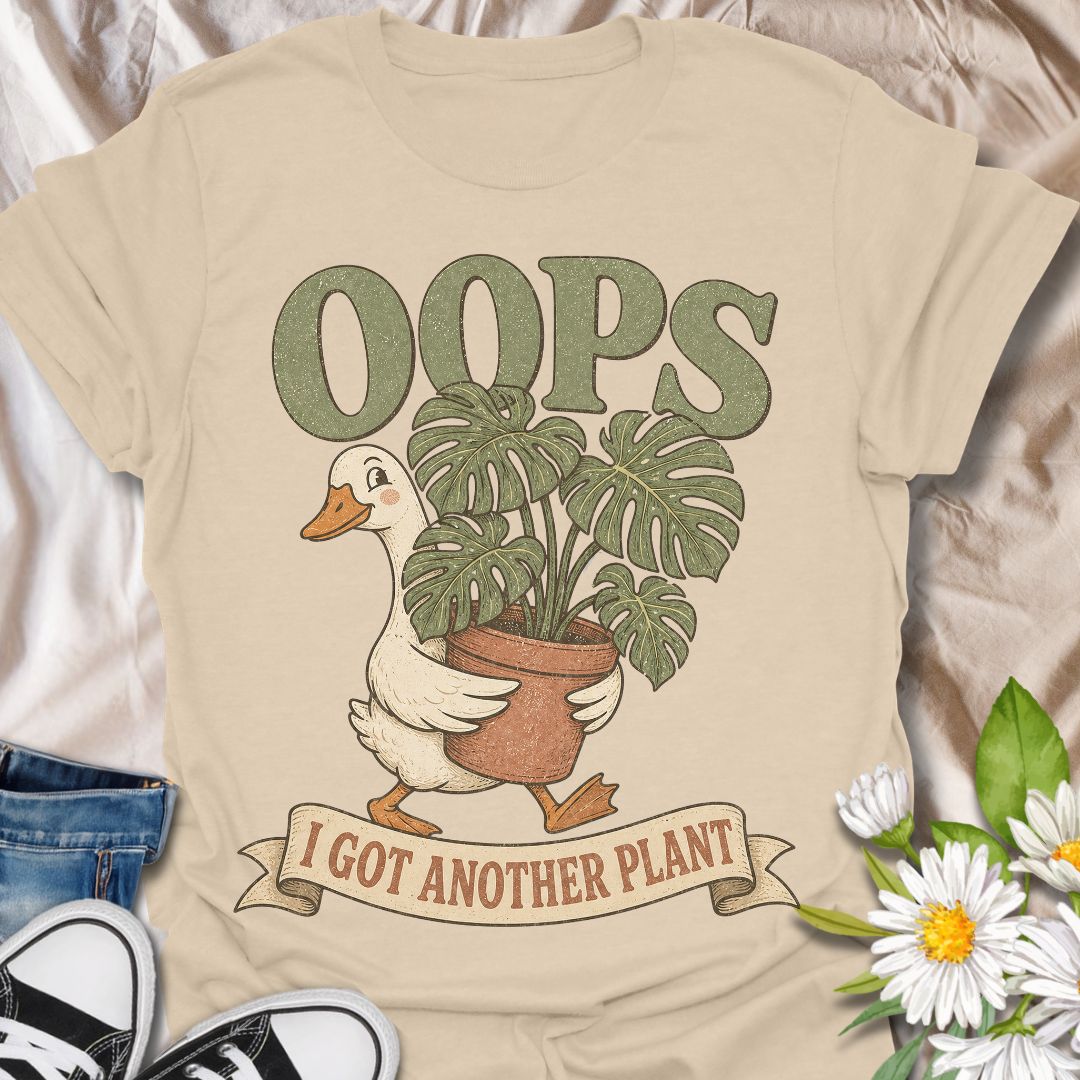 This Oops I Got Another Plant t-shirt is made for houseplant lovers who know exactly how one quick look at a plant shop turns into a new leafy addition. Featuring a cute goose carrying a potted monstera, bold retro lettering, and a playful banner design, this tee is funny, charming, and perfect for proud plant collectors. A great gift for plant moms, plant dads, indoor gardeners, propagation fans, monstera lovers, and anyone who always has room for just one more plant.