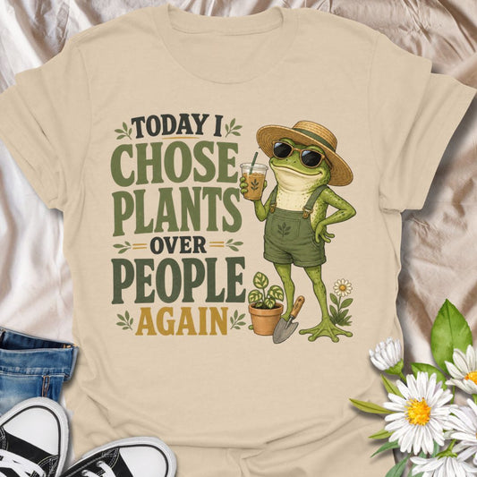 This Today I Chose Plants Over People Again t-shirt is made for plant lovers who would rather spend the day with leaves, soil, iced coffee, and zero unnecessary social plans. Featuring a smug garden frog in sunglasses, a straw hat, overalls, bold vintage lettering, and playful plant details, this design has a funny, snarky botanical vibe. Perfect for plant moms, houseplant lovers, gardeners, introverts, frog fans, and anyone who happily chooses plants over people.