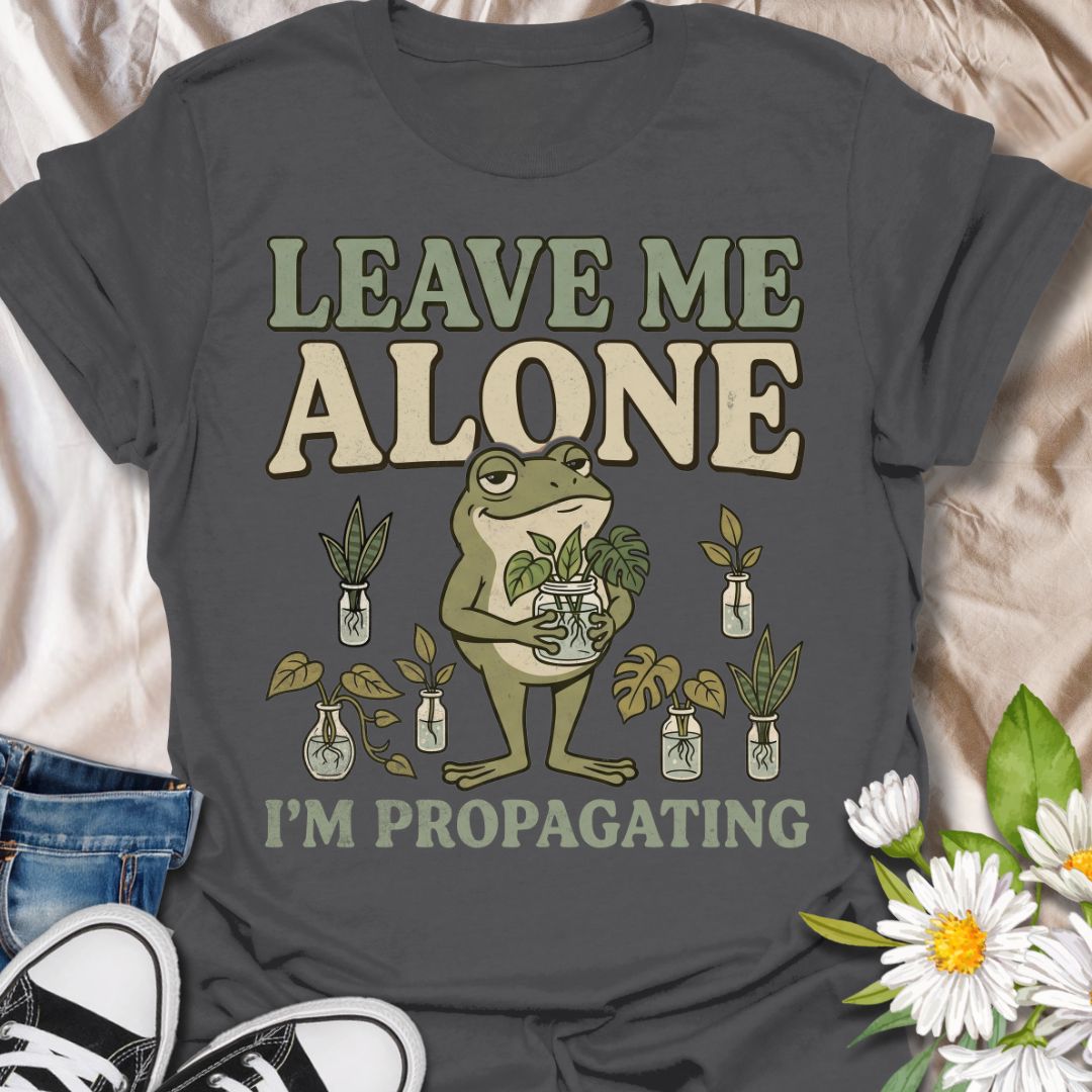 This Leave Me Alone I’m Propagating t-shirt is made for plant lovers who take cuttings, jars, roots, and quiet plant time very seriously. Featuring a smug cartoon frog holding propagated plant cuttings, surrounded by propagation jars, leafy plants, and bold retro lettering, this design has a funny botanical vibe with plenty of plant-parent attitude. Perfect for houseplant lovers, plant moms, propagation fans, indoor gardeners, frog lovers, and anyone who would rather be rooting cuttings than talking to peop