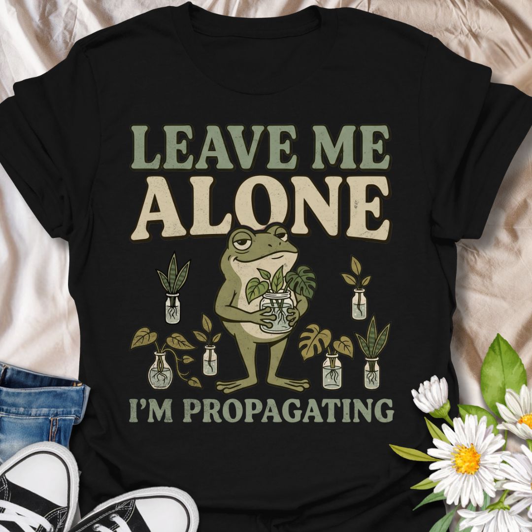 This Leave Me Alone I’m Propagating t-shirt is made for plant lovers who take cuttings, jars, roots, and quiet plant time very seriously. Featuring a smug cartoon frog holding propagated plant cuttings, surrounded by propagation jars, leafy plants, and bold retro lettering, this design has a funny botanical vibe with plenty of plant-parent attitude. Perfect for houseplant lovers, plant moms, propagation fans, indoor gardeners, frog lovers, and anyone who would rather be rooting cuttings than talking to peop