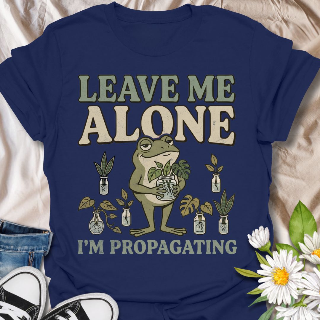This Leave Me Alone I’m Propagating t-shirt is made for plant lovers who take cuttings, jars, roots, and quiet plant time very seriously. Featuring a smug cartoon frog holding propagated plant cuttings, surrounded by propagation jars, leafy plants, and bold retro lettering, this design has a funny botanical vibe with plenty of plant-parent attitude. Perfect for houseplant lovers, plant moms, propagation fans, indoor gardeners, frog lovers, and anyone who would rather be rooting cuttings than talking to peop