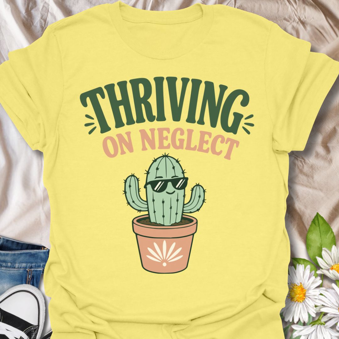This Thriving On Neglect t-shirt is made for plant lovers who relate a little too much to low-maintenance cactus energy. Featuring a cool potted cactus wearing sunglasses with bold retro lettering in green, peach, and soft cream, this design has a funny, easygoing botanical vibe. Perfect for cactus lovers, succulent fans, plant moms, plant dads, houseplant collectors, and anyone who is doing surprisingly well with minimal care.
