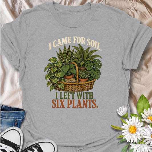 Funny houseplant T-shirt for plant lovers who visit the nursery for soil and leave with far more plants than planned. Featuring a vintage basket of lush houseplants and the line “I Came for Soil, I Left With Six Plants,” this is made for collectors who can never resist one more plant.