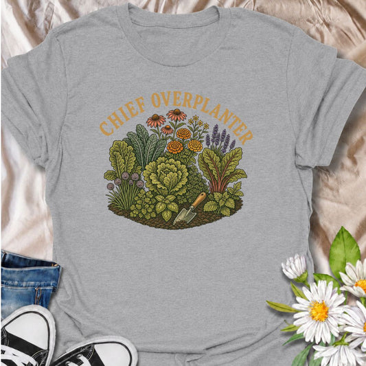 A funny gardening T-shirt for anyone who sees an empty patch of soil and immediately fills every inch of it. The “Chief Overplanter” phrase is perfect for enthusiastic gardeners who always squeeze in one more flower, herb, or vegetable. Featuring a lush garden bed packed with greenery and blooms, this design works especially well for cottage gardeners, backyard growers, and green-thumbed plant lovers. It makes a fun gift for gardeners who treat recommended spacing as more of a suggestion than a rule. Ideal 