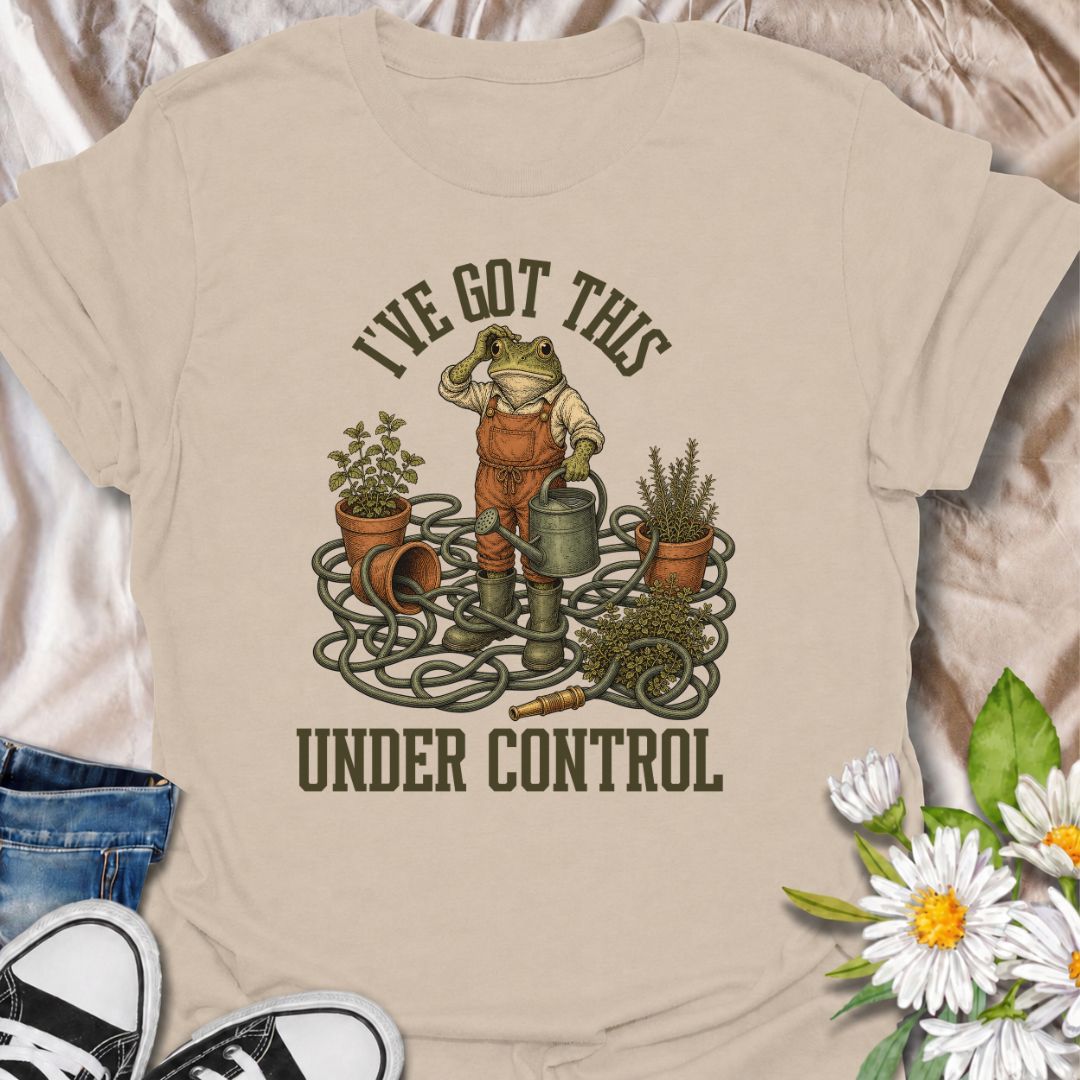 A funny gardening T-shirt for anyone who insists everything is completely under control, despite the evidence. Featuring a determined frog surrounded by tangled hose, pots, herbs, and garden tools, this design is perfect for gardeners who know chaos is part of the process. The phrase “I’ve Got This Under Control” adds dry, relatable humor without making the design feel too busy. It makes a great gift for backyard gardeners, plant lovers, and anyone who spends weekends wrestling with watering cans, hoses, an