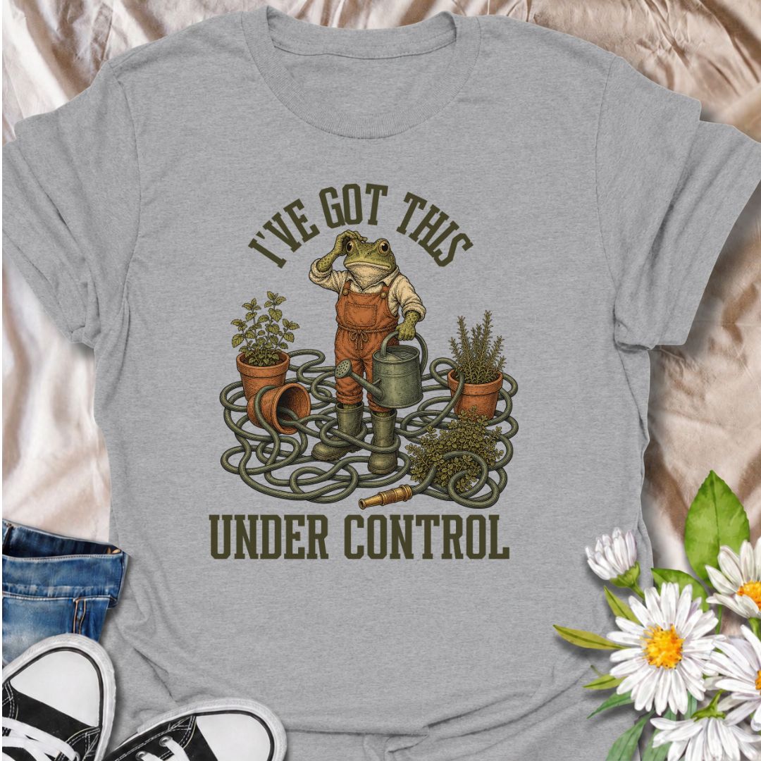 A funny gardening T-shirt for anyone who insists everything is completely under control, despite the evidence. Featuring a determined frog surrounded by tangled hose, pots, herbs, and garden tools, this design is perfect for gardeners who know chaos is part of the process. The phrase “I’ve Got This Under Control” adds dry, relatable humor without making the design feel too busy. It makes a great gift for backyard gardeners, plant lovers, and anyone who spends weekends wrestling with watering cans, hoses, an