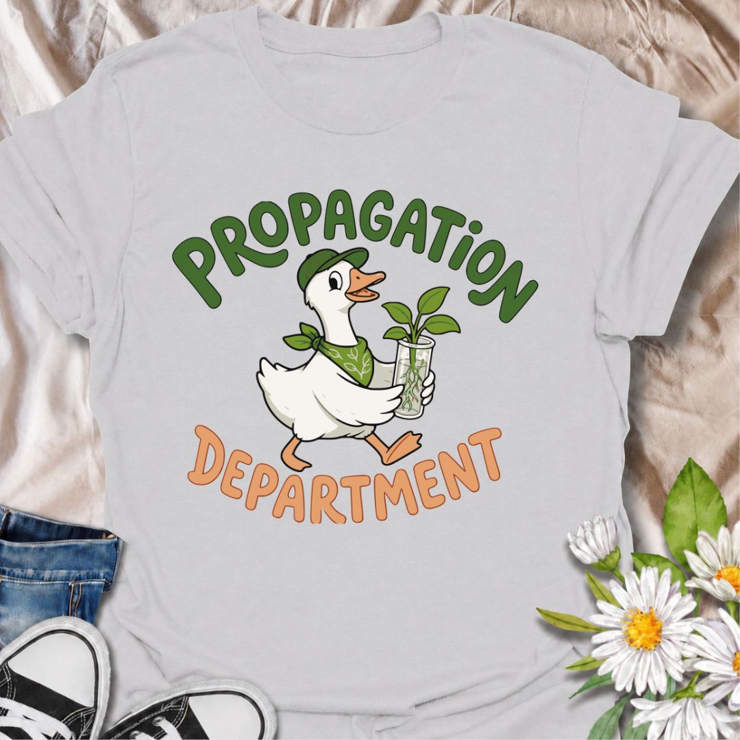 A funny propagation T-shirt for plant lovers who treat rooting cuttings like a proper department of operations. Featuring a cheerful goose carrying a fresh plant cutting in water, this design is perfect for houseplant collectors, plant parents, and propagation fans. The “Propagation Department” phrase gives the design a playful club-style feel without losing its clean, easy-to-read look. It makes a great gift for pothos lovers, indoor gardeners, and anyone with jars of cuttings taking over the counter. Idea