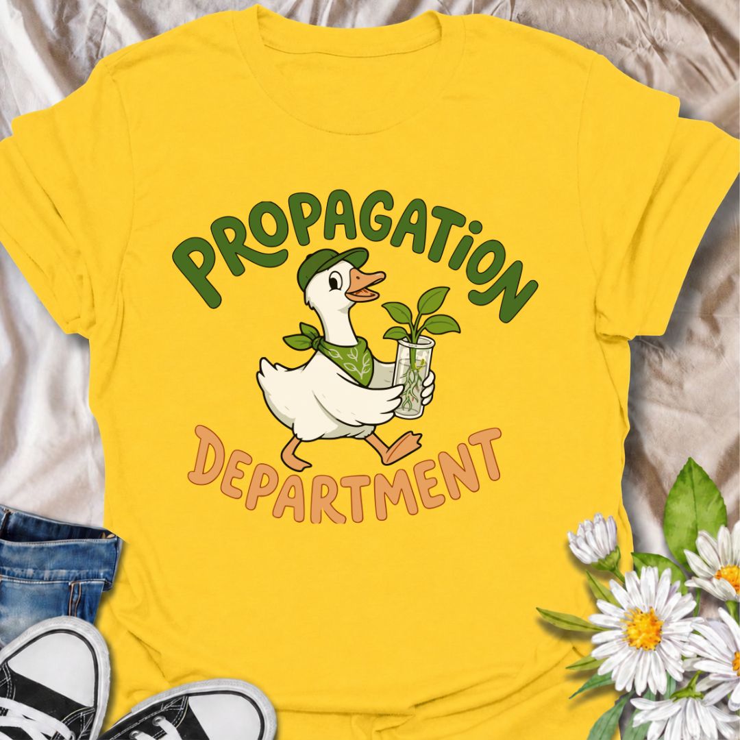 A funny propagation T-shirt for plant lovers who treat rooting cuttings like a proper department of operations. Featuring a cheerful goose carrying a fresh plant cutting in water, this design is perfect for houseplant collectors, plant parents, and propagation fans. The “Propagation Department” phrase gives the design a playful club-style feel without losing its clean, easy-to-read look. It makes a great gift for pothos lovers, indoor gardeners, and anyone with jars of cuttings taking over the counter. Idea