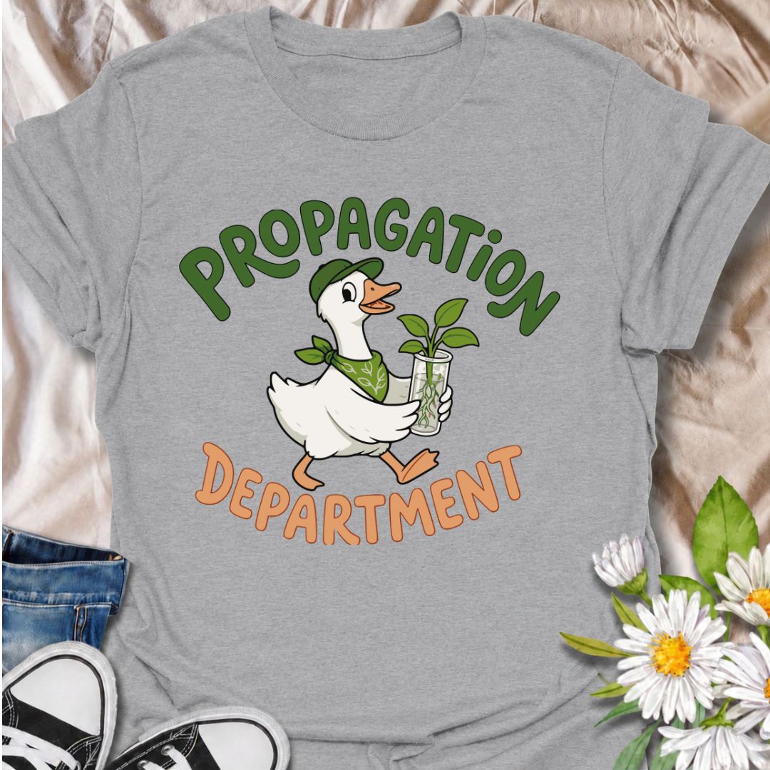 A funny propagation T-shirt for plant lovers who treat rooting cuttings like a proper department of operations. Featuring a cheerful goose carrying a fresh plant cutting in water, this design is perfect for houseplant collectors, plant parents, and propagation fans. The “Propagation Department” phrase gives the design a playful club-style feel without losing its clean, easy-to-read look. It makes a great gift for pothos lovers, indoor gardeners, and anyone with jars of cuttings taking over the counter. Idea