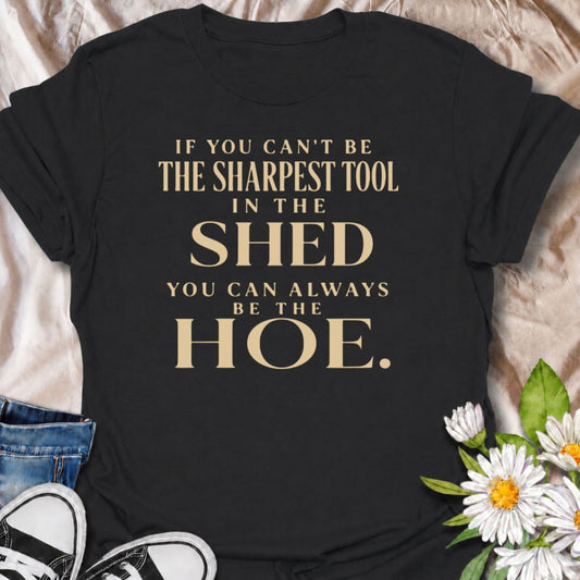 A cheeky gardening T-shirt for anyone who enjoys a slightly rude garden joke with a clever twist. The phrase “If You Can’t Be the Sharpest Tool in the Shed, You Can Always Be the Hoe” plays on classic garden-shed humor in a bold, typography-first design. It is perfect for gardeners, allotment lovers, backyard growers, and anyone with a dry sense of humor. The simple layout keeps the joke easy to read and highly wearable. A fun gift for gardeners who prefer their garden humor a little less wholesome.